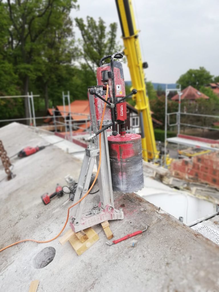 Professionelle Kernbohrung auf einer Baustelle mit Diamantbohrgerät auf Betonfläche während Dach- und Rohbauarbeiten